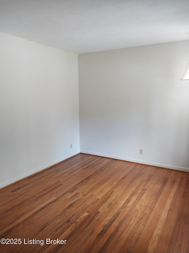 unfurnished room featuring baseboards and wood finished floors