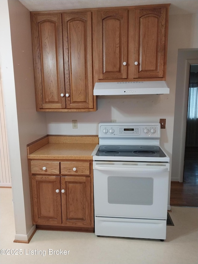 kitchen with under cabinet range hood, light countertops, white range with electric stovetop, and brown cabinetry