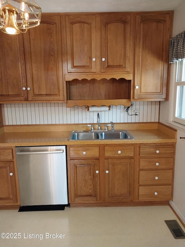 kitchen with brown cabinets, visible vents, a sink, and dishwasher