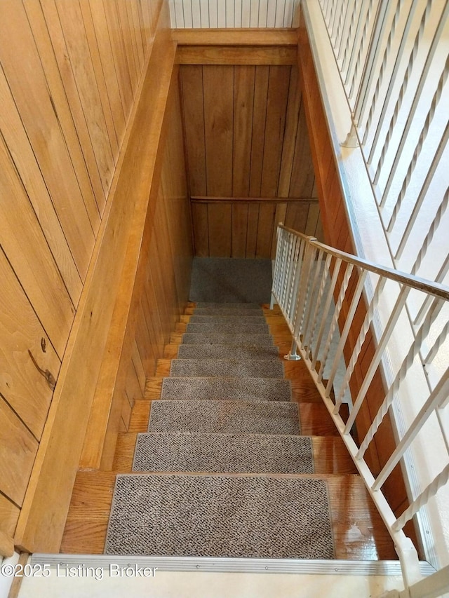 stairs featuring wood walls and wood finished floors
