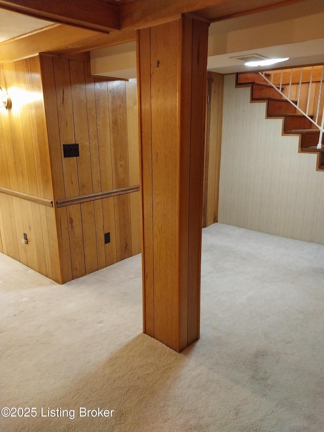 finished below grade area featuring stairs, carpet, and wooden walls