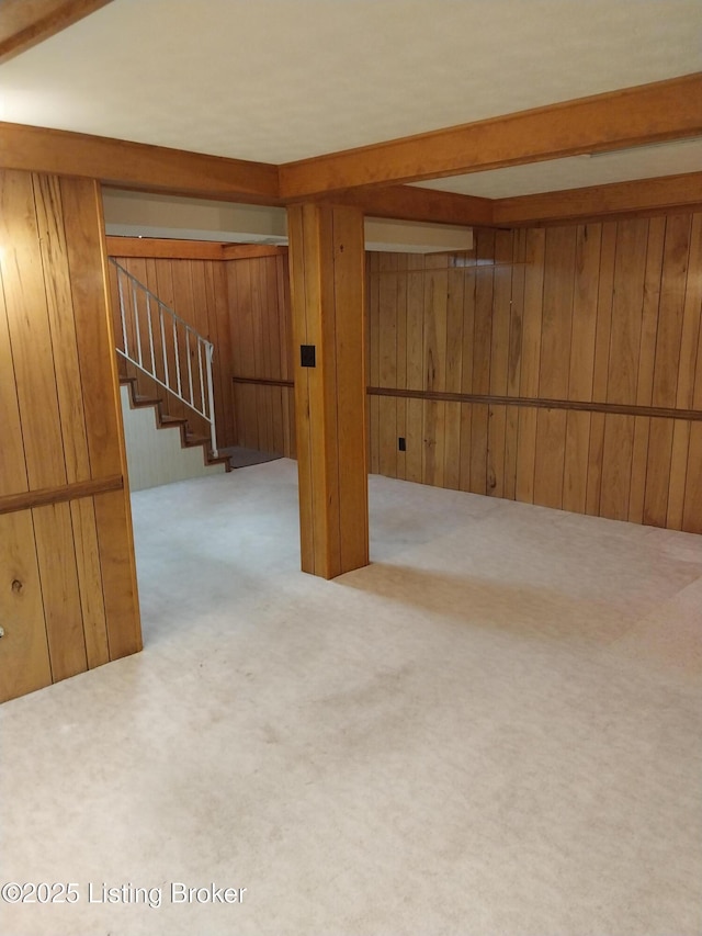 finished basement featuring stairway, wooden walls, and carpet floors