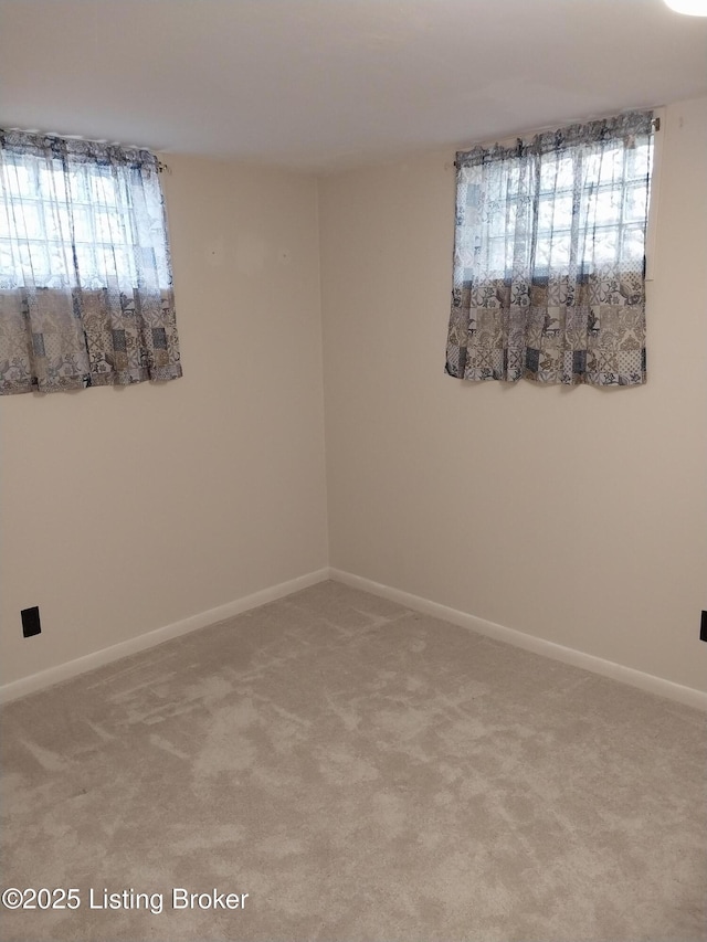 unfurnished room with baseboards and light carpet