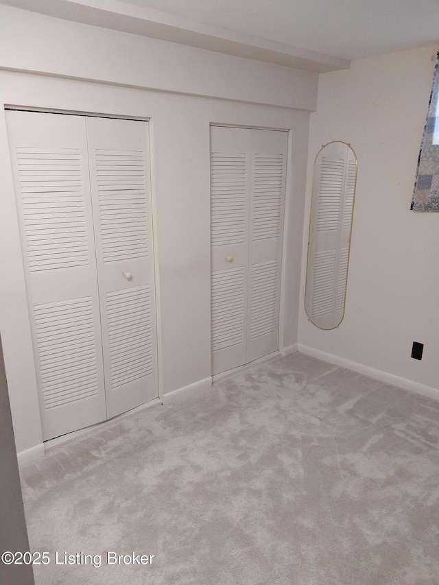 unfurnished bedroom featuring baseboards, multiple closets, and carpet floors