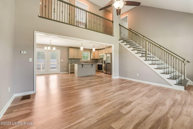 1415 Parkridge Pkwy, Louisville, KY 40214 - unfurnished living room with a ceiling fan, light wood-style floors, a chandelier, baseboards, and a towering ceiling