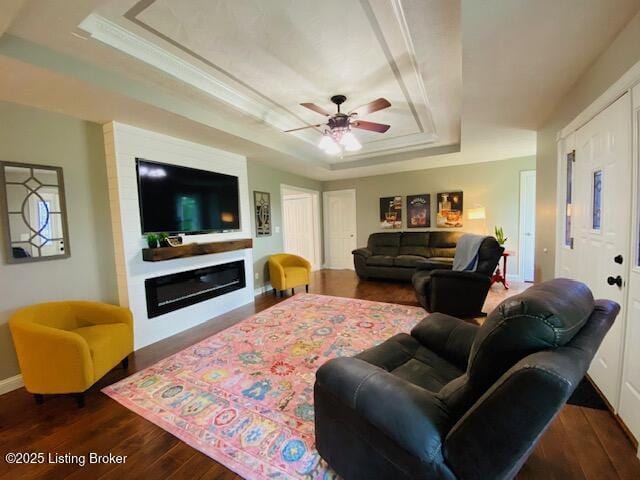 1300 Midway Ln, Springfield, KY 40069 - living area with a tray ceiling, dark wood-style floors, a glass covered fireplace, ceiling fan, and baseboards