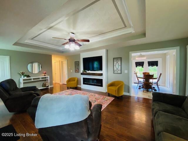 1300 Midway Ln, Springfield, KY 40069 - living area featuring a raised ceiling, dark wood-style flooring, a glass covered fireplace, a ceiling fan, and baseboards