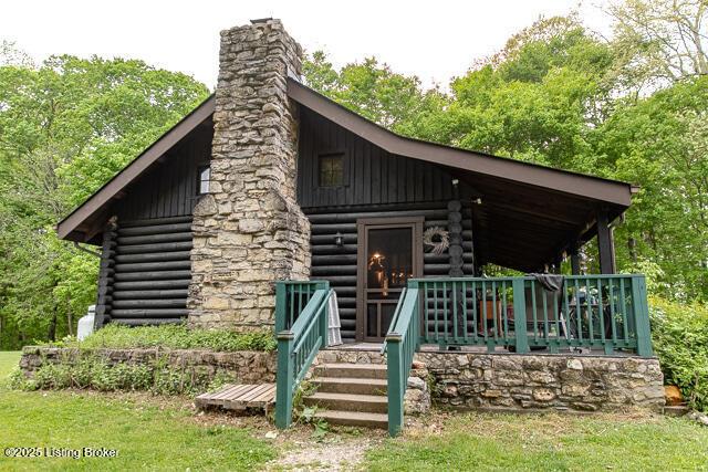 view of front facade featuring log siding, a chimney, and a porch