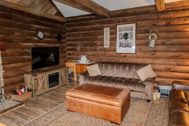 living room with lofted ceiling with beams, rustic walls, and wood finished floors