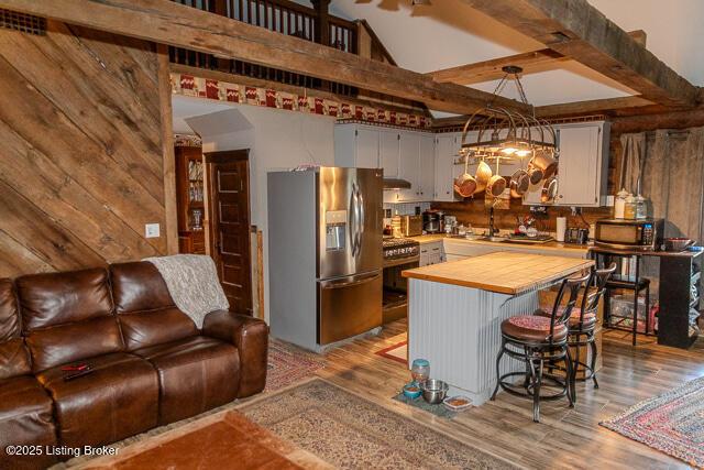 kitchen with butcher block countertops, light wood-style flooring, a breakfast bar area, open floor plan, and stainless steel appliances
