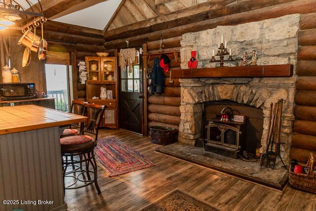 living room with log walls, wood finished floors, and lofted ceiling with beams