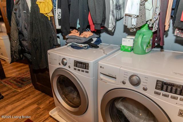 laundry area featuring washing machine and clothes dryer, laundry area, and wood finished floors