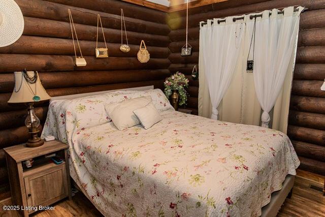 bedroom featuring rustic walls and wood finished floors