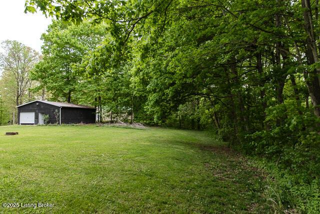 view of yard with a view of trees, an outdoor structure, and a garage