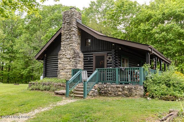 view of front of property with log siding, a front yard, a chimney, and a porch