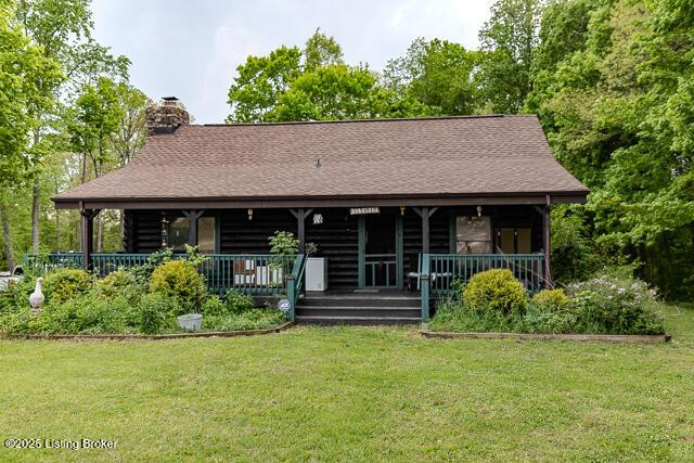 back of house featuring a porch, log exterior, a chimney, and a lawn