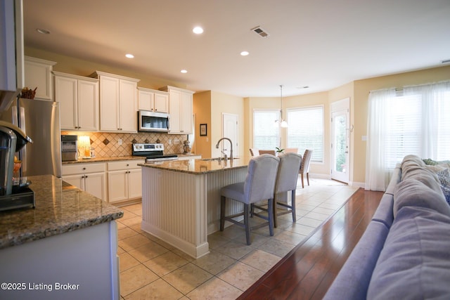 803 Urton Woods Way, Louisville, KY 40243 - kitchen with appliances with stainless steel finishes, open floor plan, a sink, tasteful backsplash, and a kitchen bar
