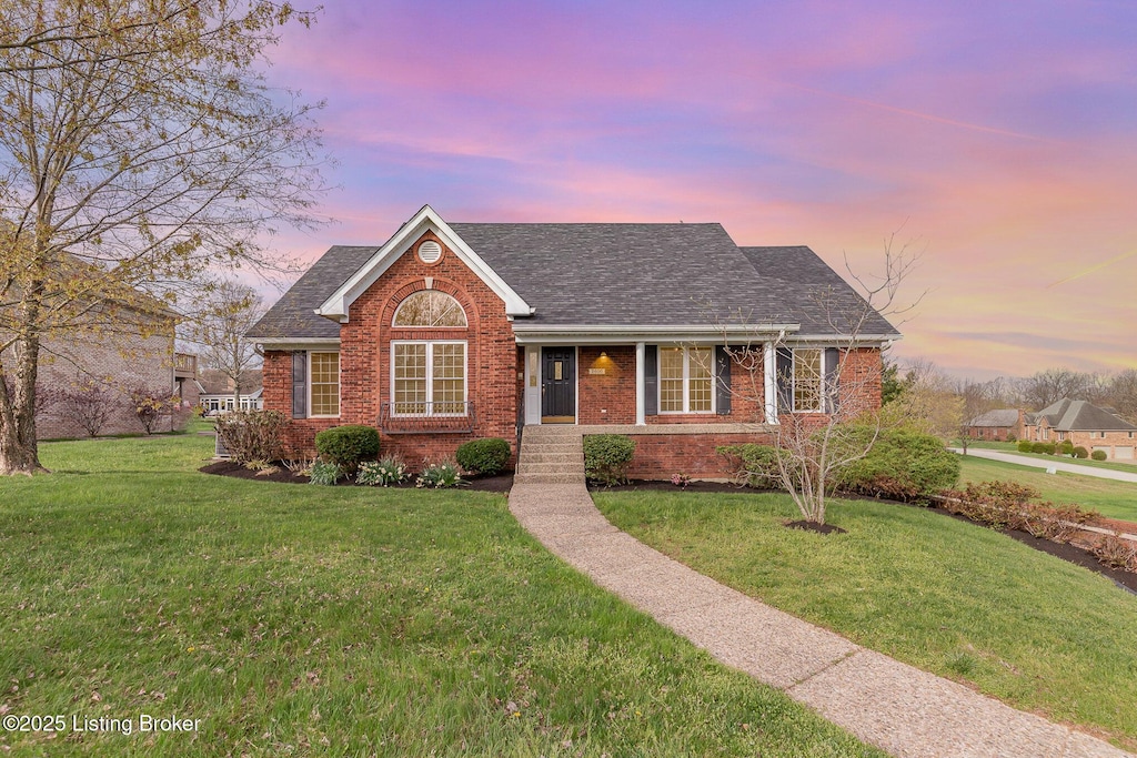 ranch-style house featuring a yard, brick siding, and a shingled roof