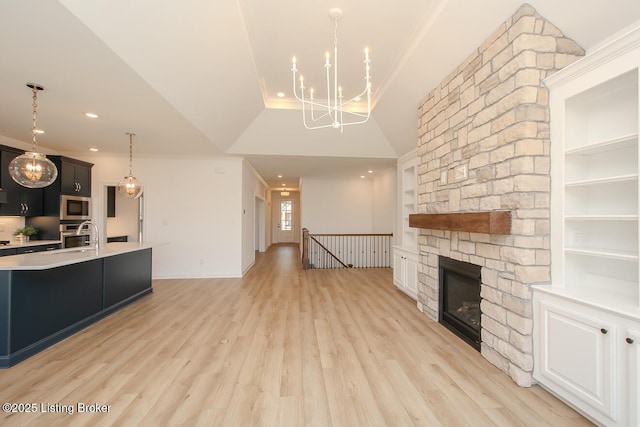 kitchen featuring decorative light fixtures, a chandelier, light wood finished floors, light countertops, and appliances with stainless steel finishes