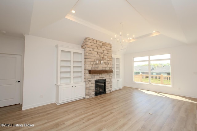 unfurnished living room with an inviting chandelier, a fireplace, a raised ceiling, light wood-style floors, and recessed lighting