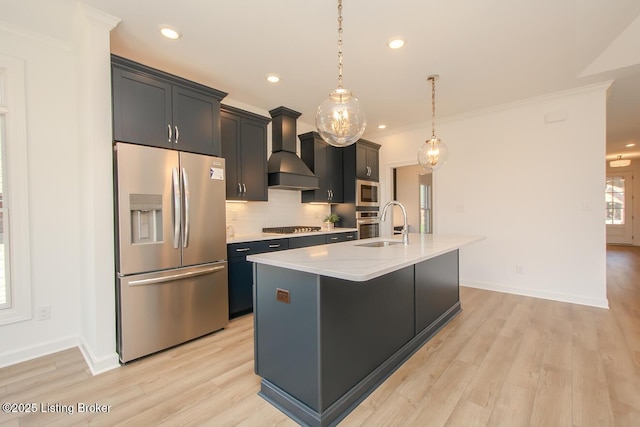 kitchen with a sink, custom range hood, decorative backsplash, stainless steel appliances, and a kitchen island with sink