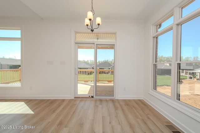 unfurnished dining area featuring an inviting chandelier, light wood-type flooring, visible vents, and baseboards