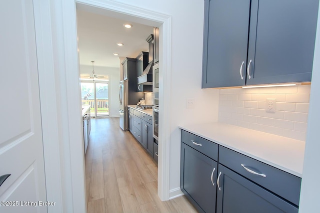 kitchen featuring recessed lighting, decorative backsplash, light wood-style floors, light countertops, and appliances with stainless steel finishes