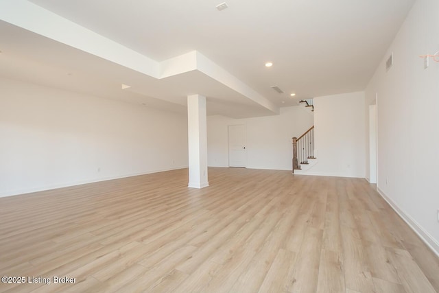 finished below grade area with light wood-type flooring, visible vents, stairs, and recessed lighting