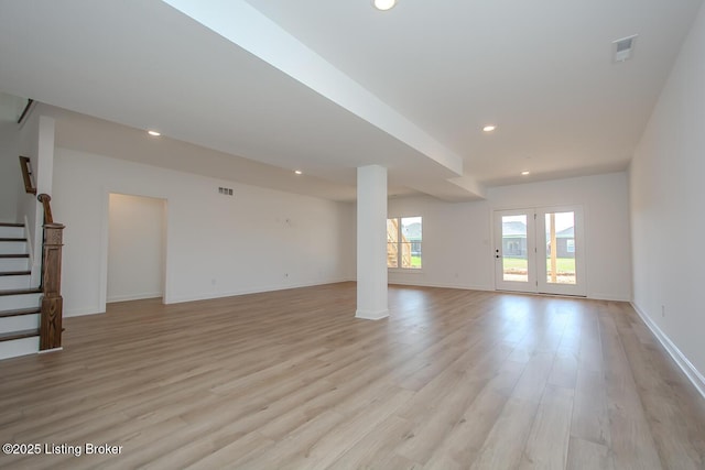 unfurnished living room featuring baseboards, stairs, light wood-style flooring, and recessed lighting