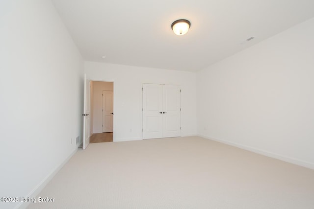unfurnished bedroom featuring light carpet, baseboards, a closet, and visible vents