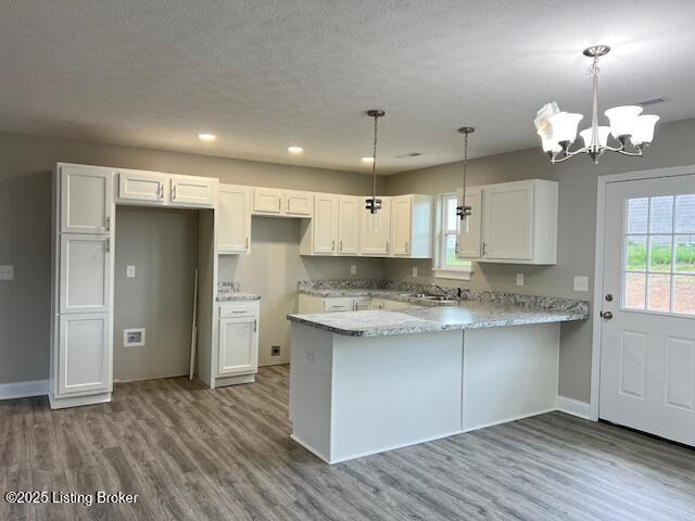 5415 Mount Holyoke Dr, Louisville, KY 40216 - kitchen with wood finished floors, a peninsula, white cabinets, a chandelier, and baseboards