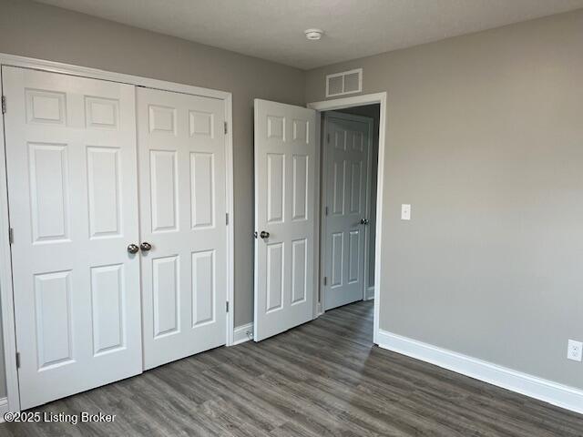 5415 Mount Holyoke Dr, Louisville, KY 40216 - unfurnished bedroom featuring baseboards, dark wood-style floors, and a closet