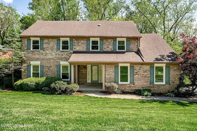 view of front facade featuring a front lawn, a shingled roof, brick siding, and a chimney
