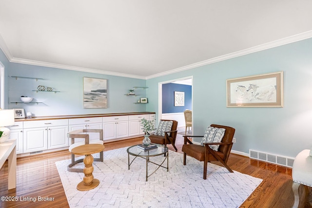 living area with ornamental molding, light wood-style floors, and baseboards