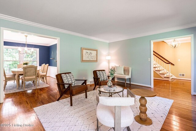 living area featuring a chandelier, crown molding, stairs, hardwood / wood-style flooring, and baseboards