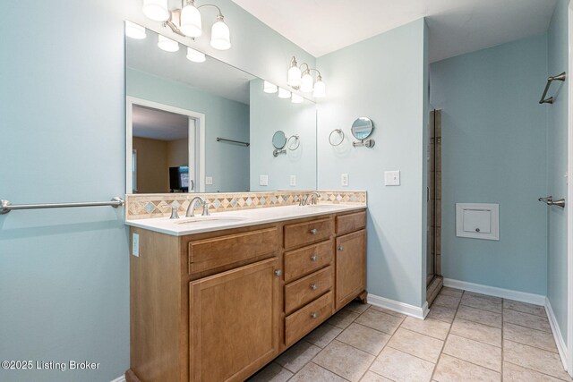 bathroom with double vanity, backsplash, tile patterned floors, an enclosed shower, and baseboards