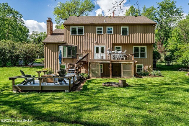 back of property featuring a deck, a chimney, a shingled roof, stairs, and a yard