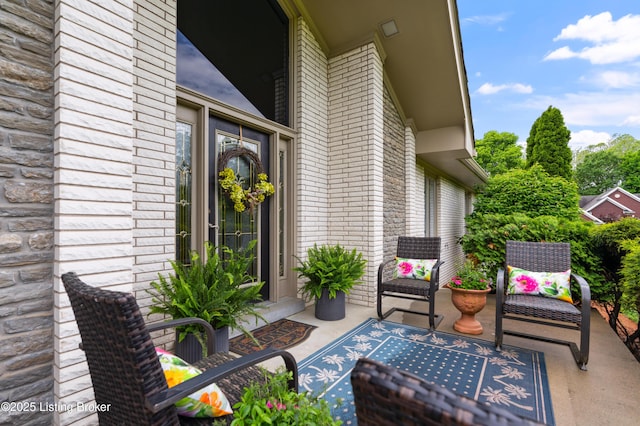 property entrance with brick siding and a patio