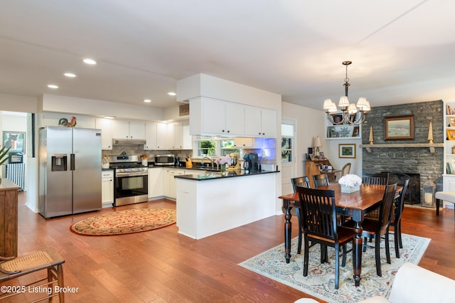 dining space with a chandelier, dark wood-style floors, recessed lighting, and a fireplace