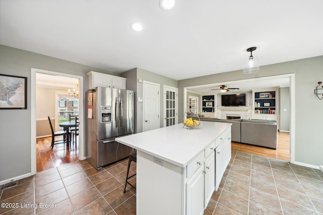 kitchen with stainless steel fridge with ice dispenser, white cabinetry, ceiling fan, baseboards, and a chandelier