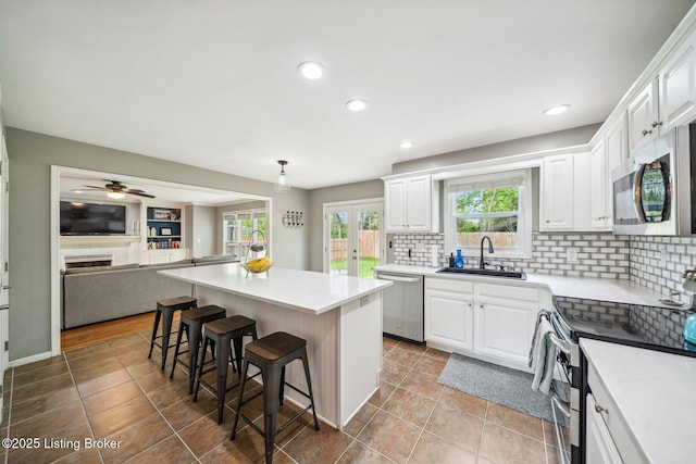 kitchen featuring appliances with stainless steel finishes, a sink, a kitchen bar, white cabinetry, and recessed lighting