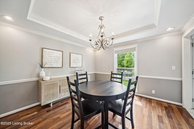 dining room with a tray ceiling, a chandelier, crown molding, wood finished floors, and baseboards