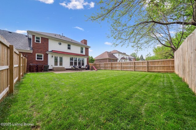 rear view of house featuring entry steps, a chimney, a patio, brick siding, and french doors