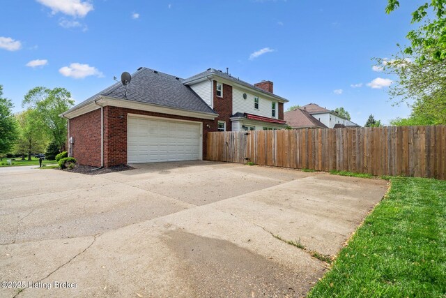 view of property exterior featuring brick siding, fence, a garage, roof with shingles, and a chimney