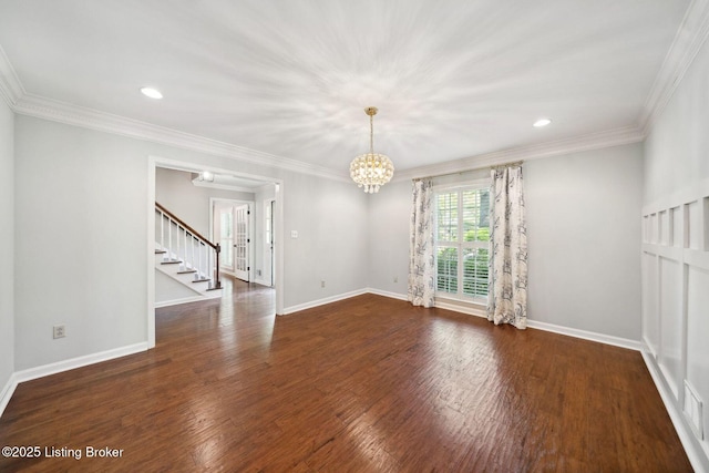 empty room featuring stairway, a chandelier, wood finished floors, baseboards, and crown molding