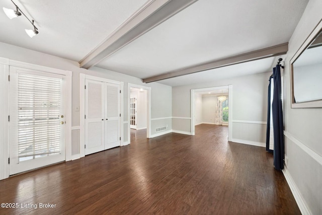 unfurnished room with beamed ceiling and wood finished floors