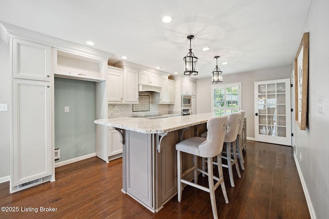 kitchen featuring appliances with stainless steel finishes, baseboards, tasteful backsplash, white cabinetry, and dark wood-type flooring