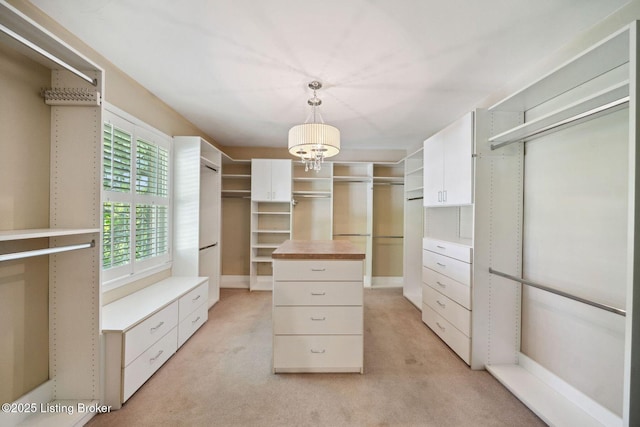 spacious closet with light carpet and a chandelier