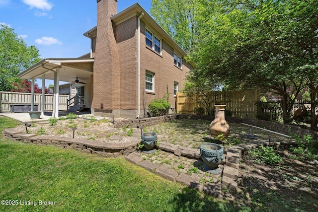 view of side of home with a ceiling fan, a chimney, brick siding, and covered porch