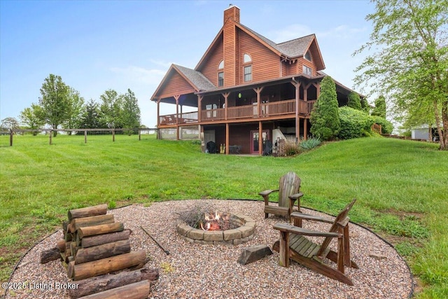back of property with an outdoor fire pit, a wooden deck, a yard, and a chimney